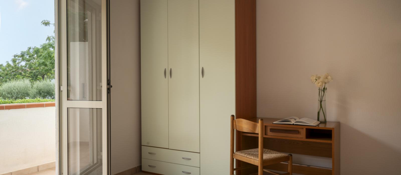 Portico con coperta decorativa, bicchieri e brocca su un muretto, ambiente rilassante.