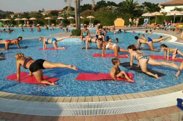 Le persone fanno esercizi su tappetini in una piscina poco profonda.