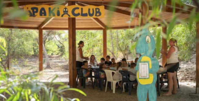 Bambini partecipano ad attività all'aperto nel Paki Club, sotto un gazebo.