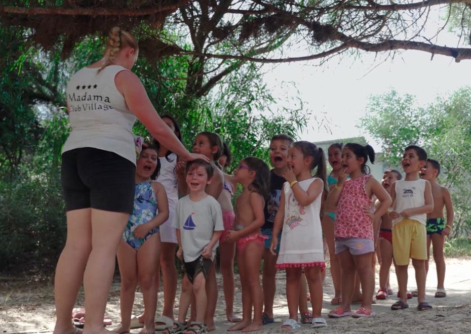 Bambini in fila sorridenti con un'animatrice al Madama Club Village.